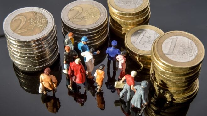 little-figurines-in-shadow-of-stacks-of-euro-coins