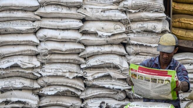 labourer-unloads-bag-of-cement-in-front-of-wall-of-bags