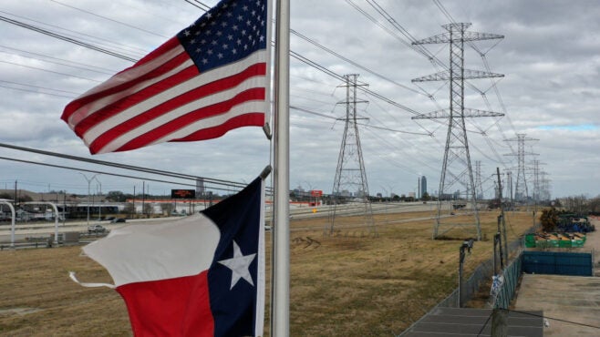 US-and-Texas-flags-flutter-in-front-of-power-transmission-towers