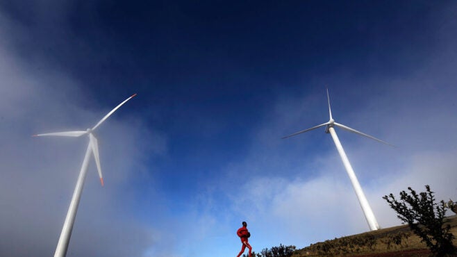 African-man-running-wind-turbine-backdrop