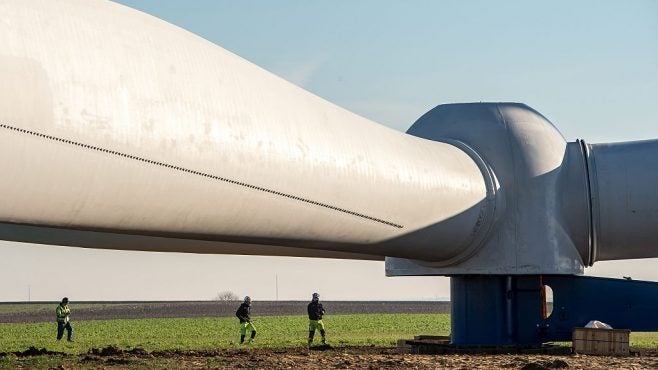 workers next to a sideways wind turbine at an installation site