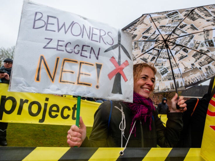A woman is holding a placard, reading 'residents say no', during a demonstration against wind turbines in the Netherlands