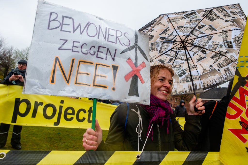 A woman is holding a placard, reading 'residents say no', during a demonstration against wind turbines in the Netherlands